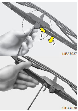 2. Compress the clip (1) and slide the blade assembly downward (2).